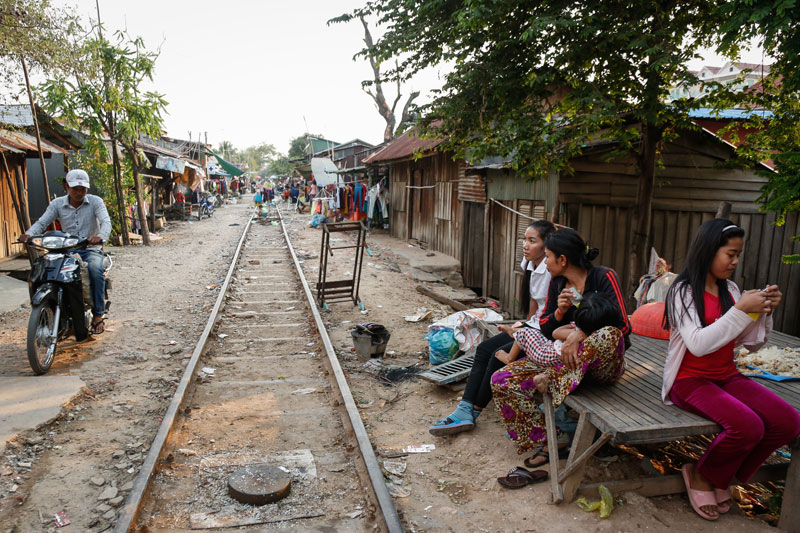 Women sit next to the tracks of an abandoned railway line that runs through a slum in Phnom Penh's Russei Keo district on Tuesday. (Siv Channa/The Cambodia Daily)