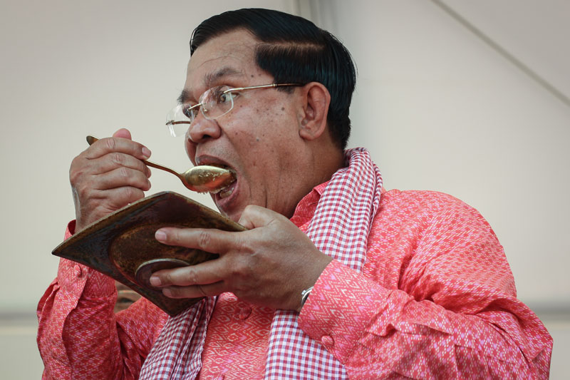 Prime Minister Hun Sen takes a bite from one of the first slices cut from the Guinness World Record-holding sticky rice cake at the Angkor Sankranta festival Tuesday. (Alex Willemyns/The Cambodia Daily)