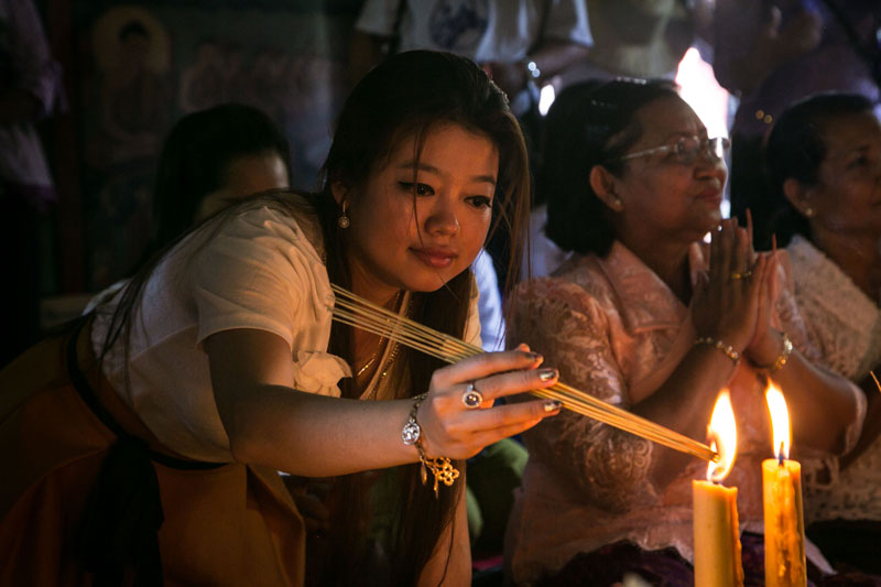 A woman lights incense during a ceremony to receive the New Year's angel at Wat Phnom on Tuesday. (Ottavia Fabbri/The Cambodia Daily)
