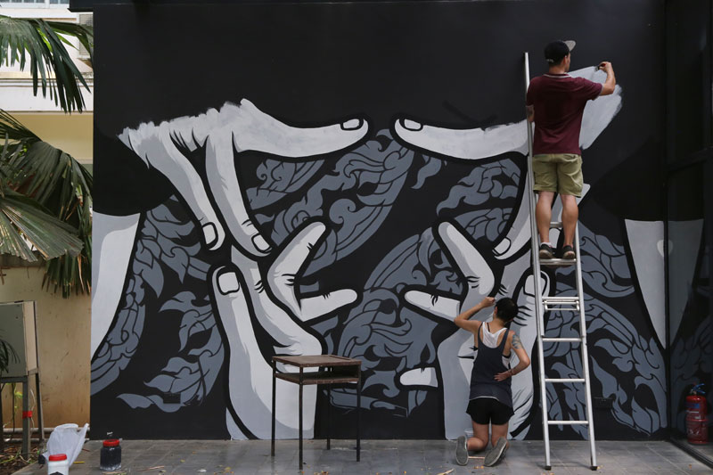 Chifumi, right, and an assistant paint a wall at the Institut Francais in Phnom Penh last week. (Aria Danaparamita/The Cambodia Daily)