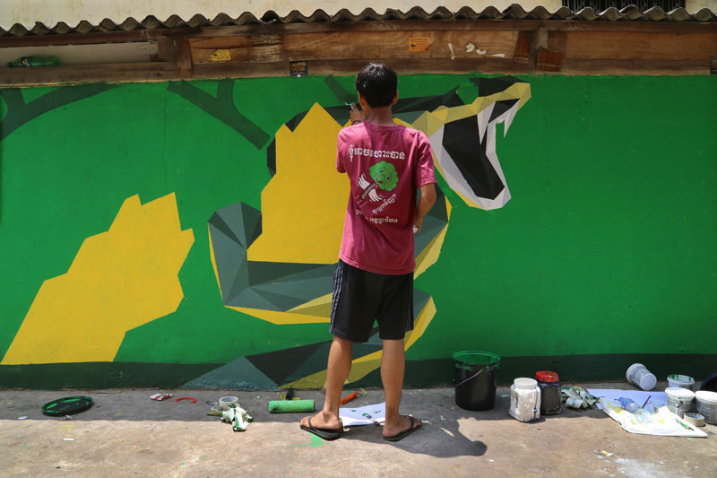 Davido paints a mural in an alleyway off Street 19 last week. (Aria Danaparamita/The Cambodia Daily)
