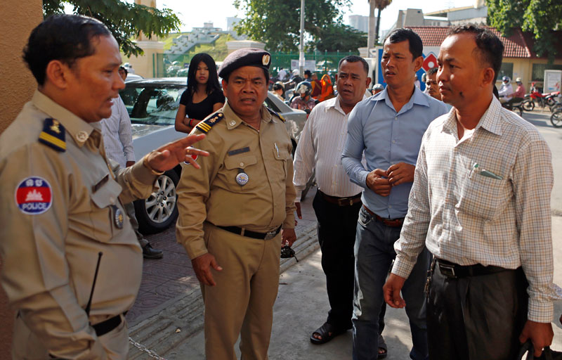 Khin Chamrouen, right, head of the CNRP Youth in Phnom Penh, speaks with police officers outside the municipal court Tuesday. (Siv Channa/The Cambodia Daily)