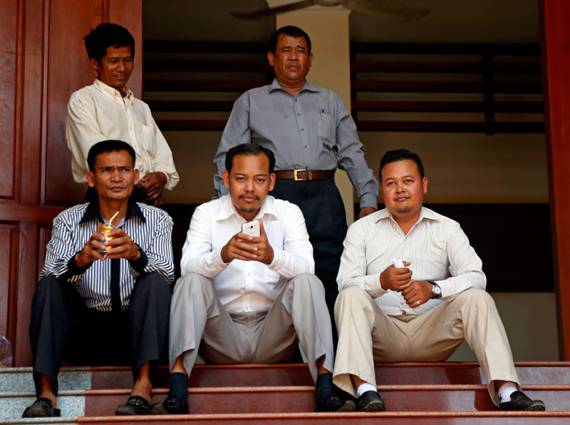 From left to right, opposition activists Ouk Pich Samnang, San Kimheng and San Seyhak sit on the stairs of the Phnom Penh Municipal Court on Tuesday. (Siv Channa/The Cambodia Daily)