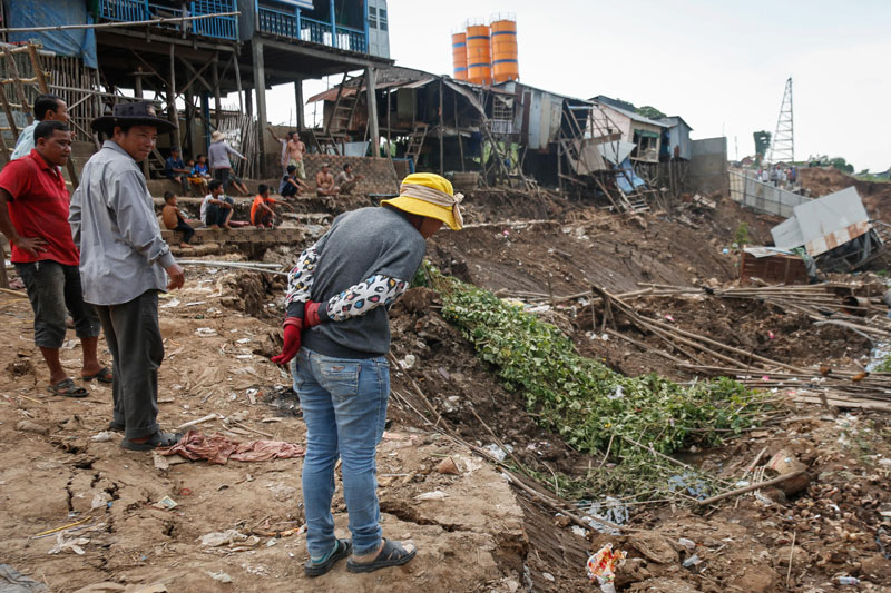 A woman inspects a collapsed piece of land along the bank of the Tonle Sap River in Phnom Penh's Russei Keo district on Monday. (Siv Channa/The Cambodia Daily)