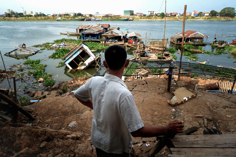 A resident of Phnom Penh's Russei Keo district looks out Thursday at houses that collapsed into the Tonle Sap river on Sunday. (Matt Walker)