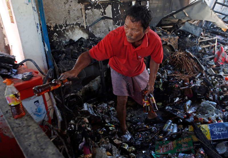 A man sorts through the wreckage of a home in Phnom Penh's Sen Sok district where four people died in a fire Thursday. (Siv Channa/The Cambodia Daily)