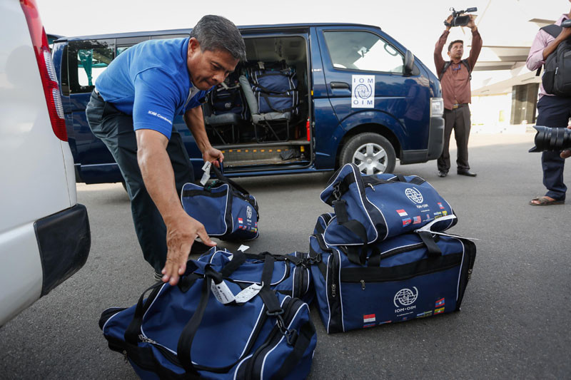 An employee of the International Organization for Migration loads bags belonging to repatriated fishermen into a van yesterday at the Phnom Penh International Airport. (Siv Channa/The Cambodia Daily)