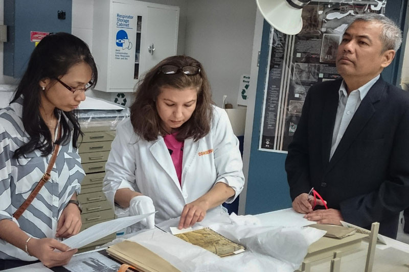 Documentation Center of Cambodia director Youk Chhang, right, and Sirik Savina, left, watch as a Khmer Rouge artifact is unwrapped at the US Holocaust Memorial Museum in Washington on May 4. (Men Pechet/Documentation Center of Cambodia) 
