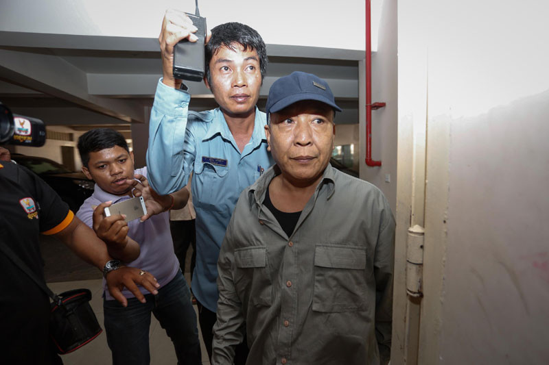 Former Meanchey district police chief Hy Narin, right, enters the Phnom Penh Municipal Court on Monday. (Siv Channa/The Cambodia Daily)
