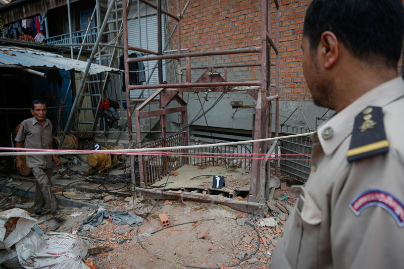 A police officer inspects a construction elevator that fell four stories at a building site in Phnom Penh's Chamkar Mon district on Thursday while carrying four workers, killing three. (Siv Channa/The Cambodia Daily)