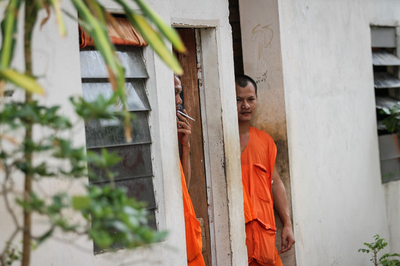 A monk smokes a cigarette near a dormitory in Wat Samakki Raingsey. (Siv Channa/The Cambodia Daily)