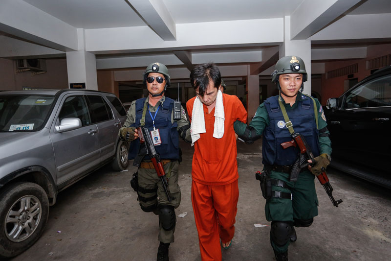 Police officers from the Interior Ministry's anti-drug department escort Liv Seu out of the Phnom Penh Municipal Court on Monday after he was charged with drug trafficking, manufacturing and possession. (Siv Channa/The Cambodia Daily)