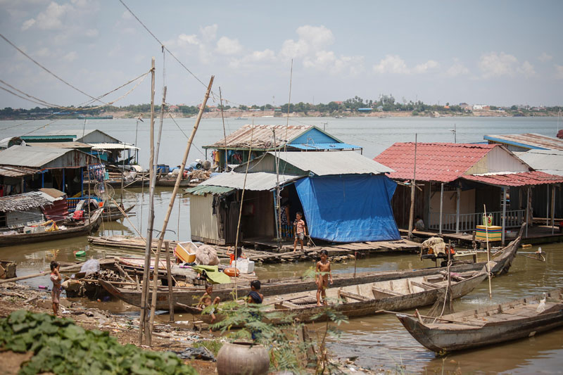 Children stand on fishing boats and floating homes near the Akrei Khsat ferry terminal on the Mekong River on Wednesday. (Siv Channa/The Cambodia Daily)