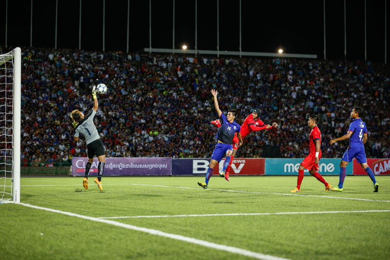 Goalkeeper Sou Yaty saves a header from Singapore's Fazrul Nawaz at Phnom Penh's Olympic Stadium on Thursday. (Siv Channa/The Cambodia Daily)