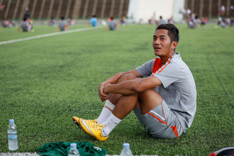 Injured footballer Prak Mony Udom sits out of the national team's practice Monday night at Olympic Stadium. (Siv Channa/The Cambodia Daily)