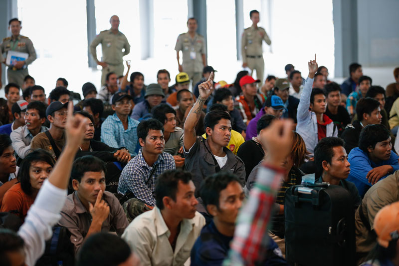 Cambodian fishermen who arrived from Indonesia on Thursday raise their hands to signal the province they hail from as officials at Phnom Penh's Chroy Changva district office prepare to send them home. (Siv Channa/The Cambodia Daily)