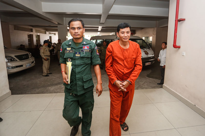 Hang Vuthy is escorted into the Phnom Penh Municipal Court         on Wednesday ahead of his retrial over a 2007 prison escape. (Siv Channa/The Cambodia Daily)