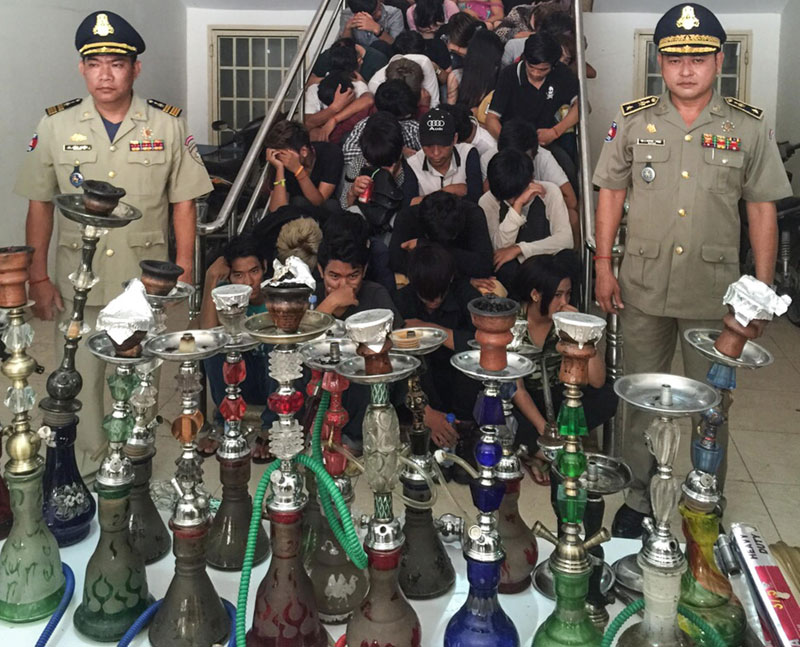 Police officers pose at the Interior Ministry Friday night after seizing 20 water pipes and detaining 50 people found smoking shisha at a nightclub in Phnom Penh's Chamkar Mon district, in a photo provided by police.
