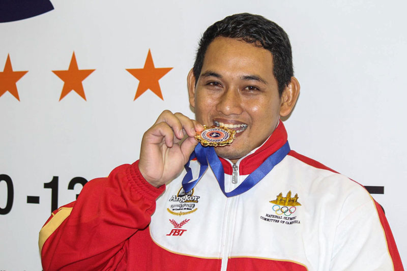 Dorn Sov bites his gold medal after winning first place in the 96-kg freestyle weight class at the Southeast Asia Wrestling Championships in Singapore on Saturday. (Thin Vichet)