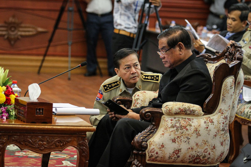 National Police Commissioner Neth Savoeun, left, speaks to Interior Minister Sar Kheng on Wednesday during a meeting about illegal immigration at the ministry in Phnom Penh. (Siv Channa/The Cambodia Daily)