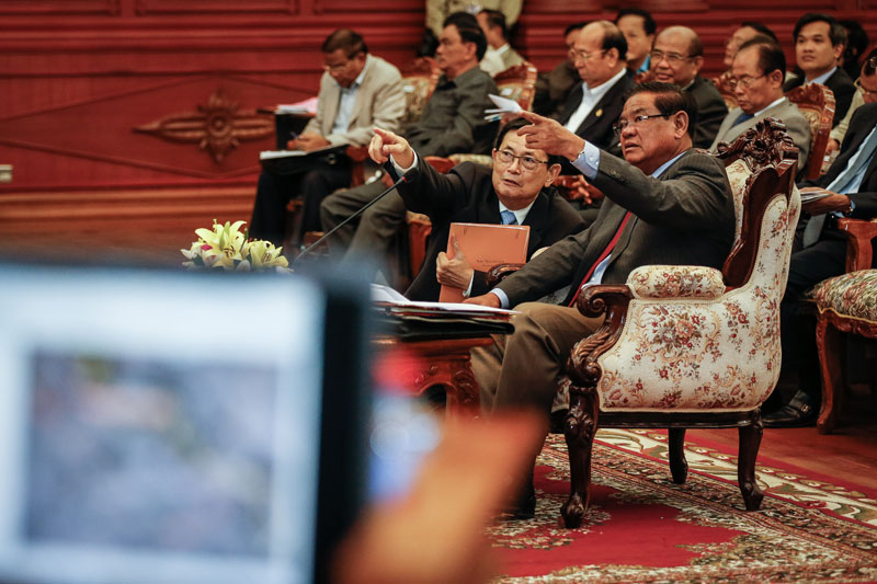 Interior Minister Sar Kheng, right, and border affairs chief Var Kimhong gesture during a meeting in Phnom Penh on Tuesday with government officials from the provinces bordering Vietnam. (Siv Channa/The Cambodia Daily)