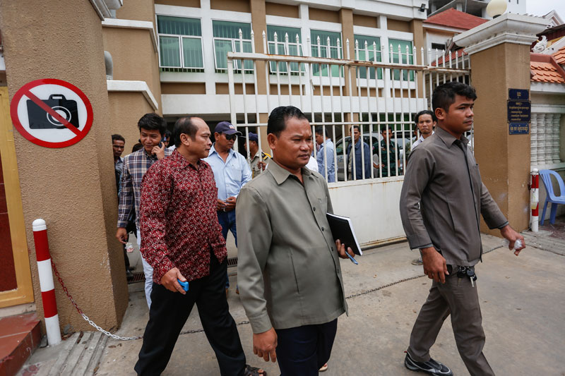 Daun Penh district security chief Kim Vutha, center, and district guard Norm Phalla, left, leave the Phnom Penh Municipal Court on Monday. (Siv Channa/The Cambodia Daily)