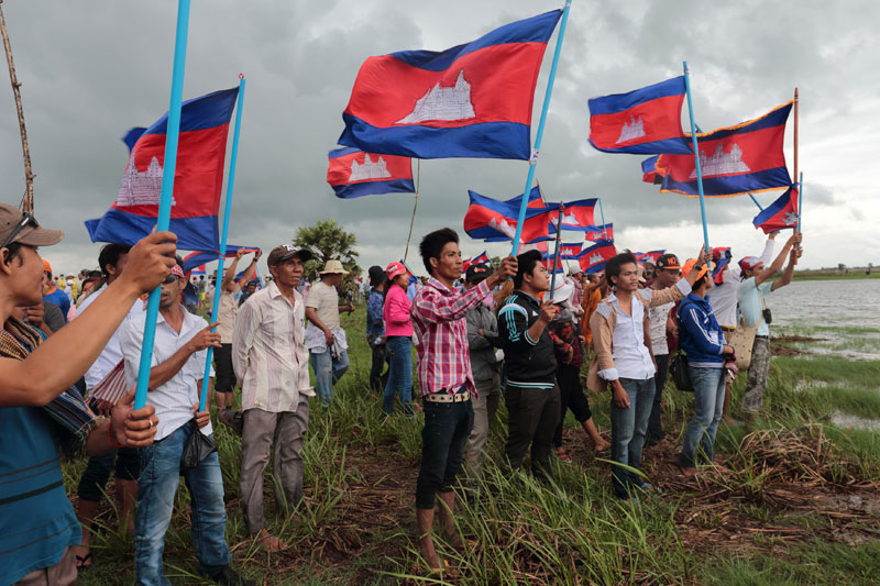 CNRP activists hold Cambodian flags near the Vietnamese border in Svay Rieng province on Sunday during an opposition-led trip to a disputed border post in Kompong Ro district. (Satoshi Takahashi)