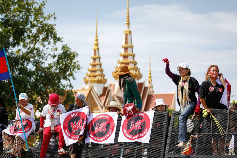 Women climb metal barricades outside the National Assembly in Phnom Penh on Tuesday during a protest against a draft law that would regulate the country's NGOs and associations. (Siv Channa/The Cambodia Daily)