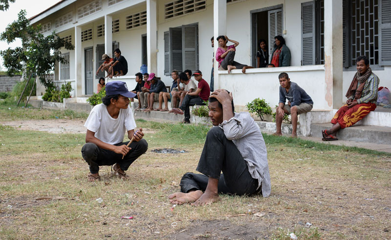 A guard, left, squats among detainees at the Pur Senchey Vocational Training Center in Phnom Penh last year. (Alex Consiglio/The Cambodia Daily)