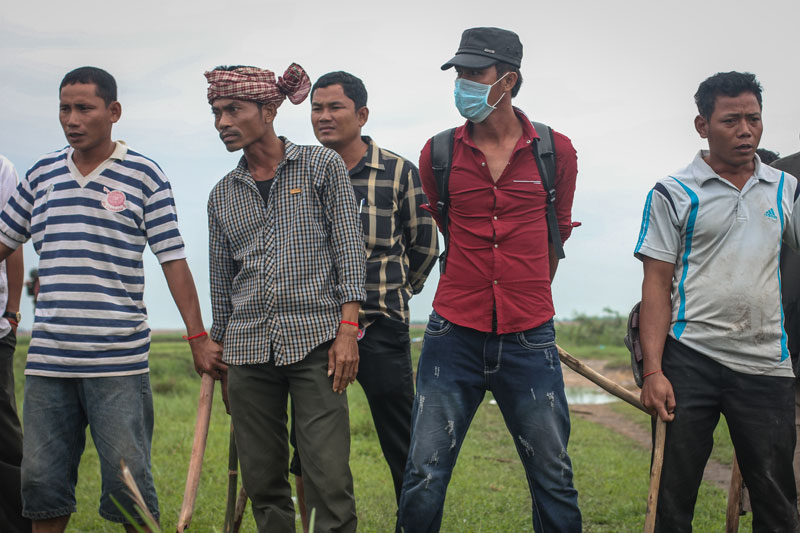 A group of men armed with clubs block the way to border post 203 in Svay Rieng province's Kompong Ro district on Sunday. (Alex Willemyns/The Cambodia Daily)