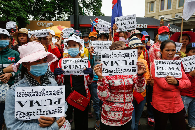 Akeentex workers hold signs that read 'The buyer PUMA has to solve the problem' at a protest outside the Phnom Penh Municipal Court on Monday. (Siv Channa/The Cambodia Daily)