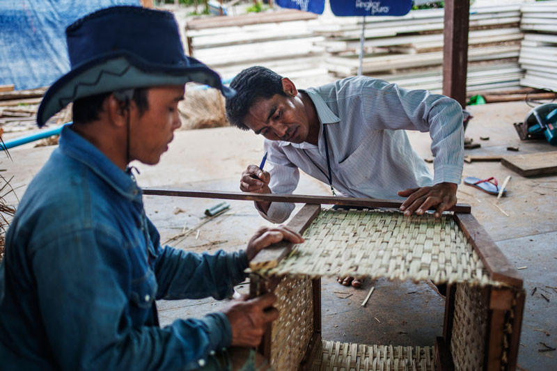 Thean Chantha, right, makes a wastebasket at the Sok San Beach Resort. (Jens Welding Ollgaard/The Cambodia Daily)