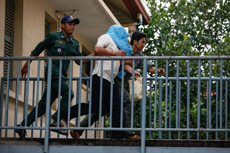 Police escort former Phnom Penh Municipal Court Director Ang Mealaktei across a walkway at the Kandal Provincial Court on Sunday. (Siv Channa/The Cambodia Daily)