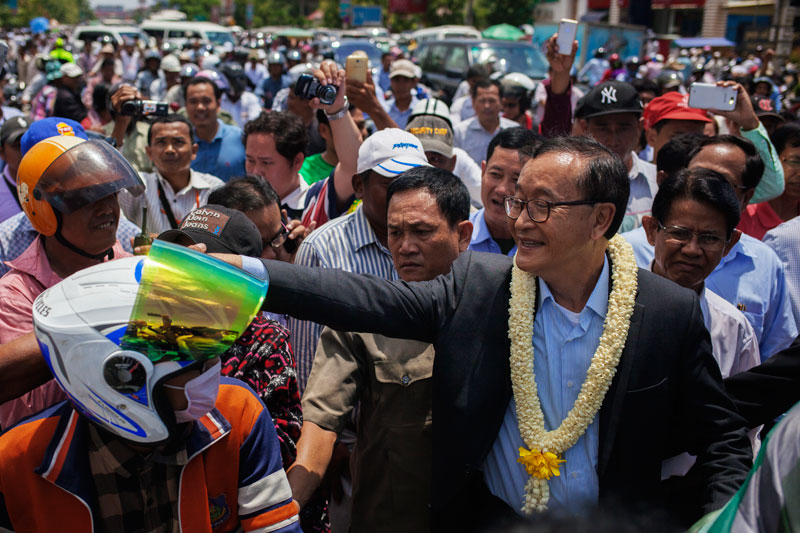 Opposition leader Sam Rainsy greets supporters at Phnom Penh International Airport on Sunday after returning from abroad. (Jens Welding Ollgaard/The Cambodia Daily)