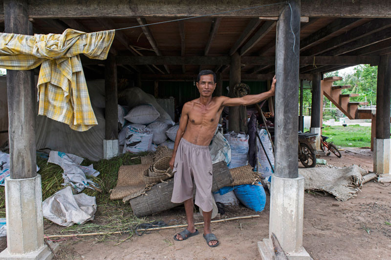 Rice farmer Nep Sokhom stands under his house. (Peter Ford/The Cambodia Daily)