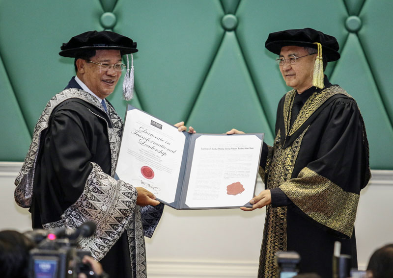 Prime Minister Hun Sen, left, receives an honorary doctorate from Raja Aznil, senior vice president of Malaysia's Limkokwing University, during a ceremony in Phnom Penh on Wednesday. (Khem Sovannara)