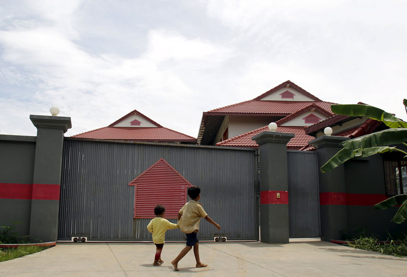 Two boys walk past the Phnom Penh villa serving as the temporary housing for the first four refugees from Nauru last week. (Pring Samrang/Reuters)
