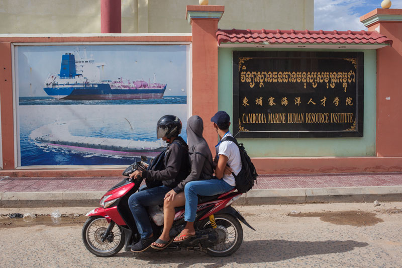 Young men drive past the Cambodia Marine Human Resource Institute in Phnom Penh's Stung Meanchey district on Tuesday. (Jens Welding Ollgaard/The Cambodia Daily)