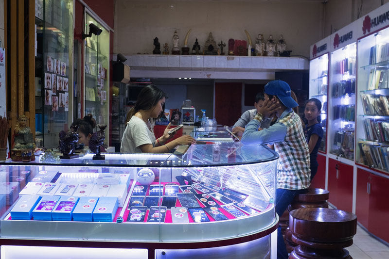Customers sit inside a mobile phone shop on Sihanouk Boulevard in Phnom Penh on Thursday. (Jens Welding Ollgaard/The Cambodia Daily)