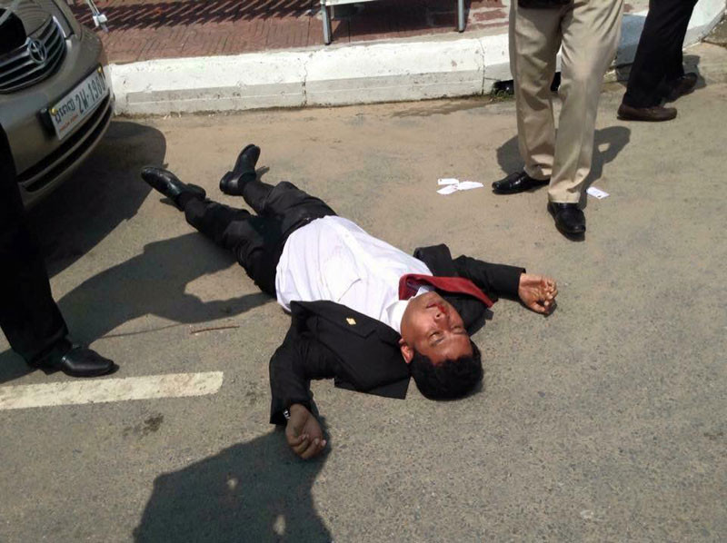 CNRP lawmaker Nhay Chamroeun lies on a road outside the National Assembly after he was beaten by a group of protesters yesterday. (Oun Pov)