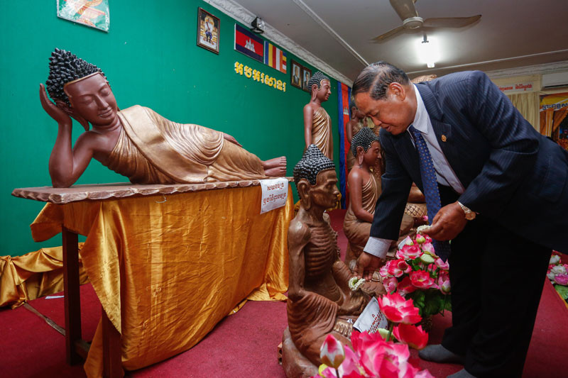 Cults and Religion Minister Min Khin places an ornament on a statue of the Buddha during an event at his ministry in Phnom Penh Tuesday. (Siv Channa)