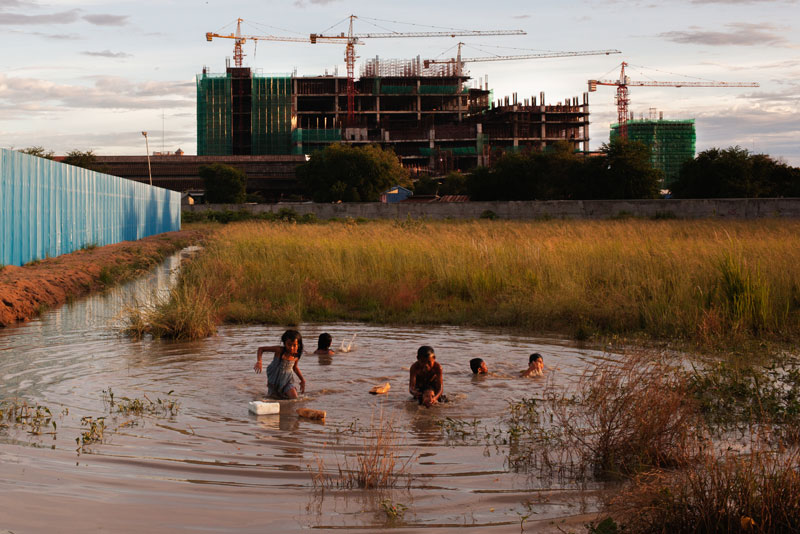 Children play in a pool of water this week on land near the development site of One Park, which a Chinese firm began building last month on the former Boeng Kak lake area in Phnom Penh. (Jens Welding Ollgaard/The Cambodia Daily)