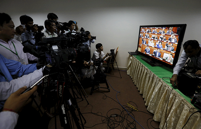 Journalists gather around a television in the National Assembly's media room as CPP lawmakers vote to remove deputy opposition leader Kem Sokha as first vice president of the Assembly on Friday morning. (Reuters) 