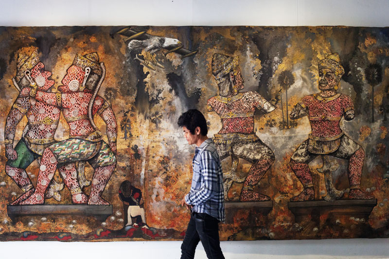 Leang Seckon and his mixed media artwork, ‘Indochina War,’ in his studio in Phnom Penh (Jens Welding Ollgaard/The Cambodia Daily)