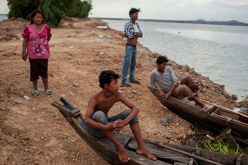 Khun Pheap, left, looks out over the dirt quarry on Thursday that her husband's fishing boat was sucked into after the wall separating it from Kop Srov lake collapsed on Tuesday night. (Jens Welding Ollgaard/The Cambodia Daily)