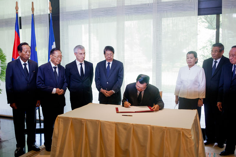 Prime Minister Hun Sen signs a condolence book at the French Embassy in Phnom Penh on Monday, flanked by senior government officials and French Ambassador Jean-Claude Poimboeuf, third from left. (Jens Welding Ollgaard/The Cambodia Daily)
