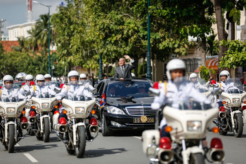 King Norodom Sihamoni rides in a car on Phnom Penh's Suramarit Boulevard as his motorcade leaves a ceremony at Independence Monument marking 62 years since Cambodia declared its independence from France. (Siv Channa)
