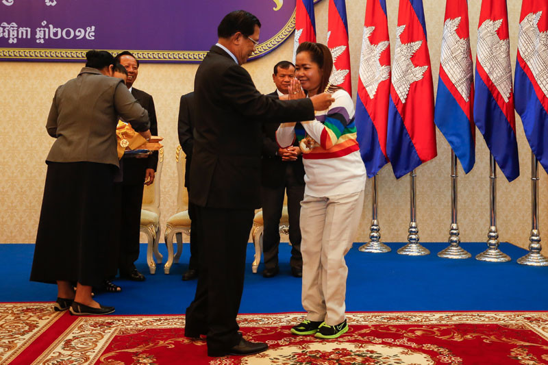 Prime Minister Hun Sen presents a medal to petanque player Ke Leng during a ceremony at the prime minister's office building in Phnom Penh on Tuesday to celebrate Ms Leng's world championship win. (Siv Channa/The Cambodia Daily)