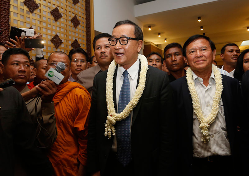Opposition leaders Sam Rainsy, middle, and Kem Sokha speak to reporters at the Phnom Penh International Airport last night. (Siv Channa)