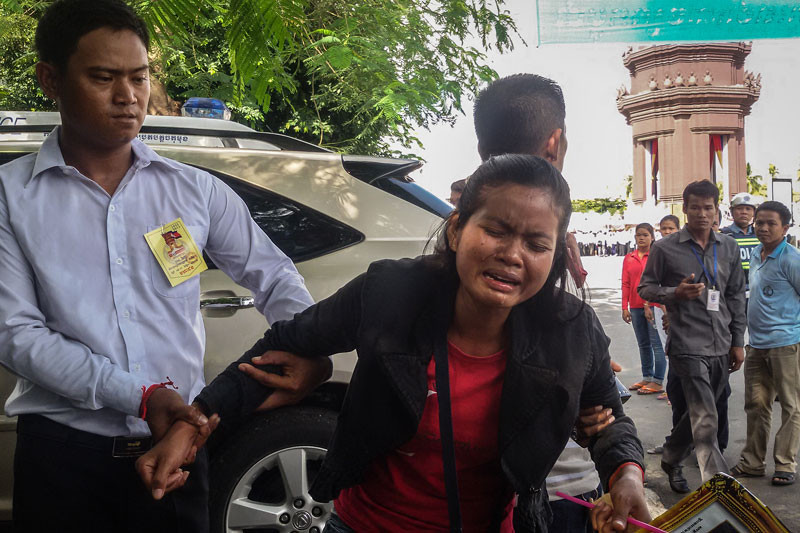 Khy Sovuthy/The Cambodia Daily Khlork Yousara is restrained after running toward King Norodom Sihamoni during an Independence Day event in Phnom Penh on Monday.